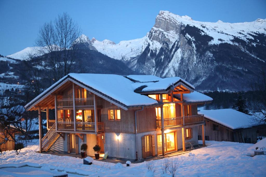 une cabane en rondins dans la neige avec une montagne dans l'établissement Chalet Brio, à Samoëns