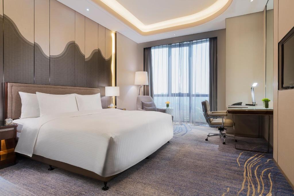 a bedroom with a large white bed and a desk at Wanda Realm Changzhou in Changzhou