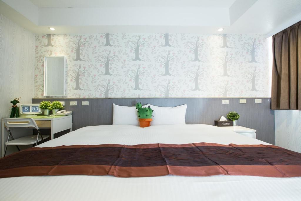 a bedroom with a large white bed and a desk at Taipei Toy Hotel in Taipei