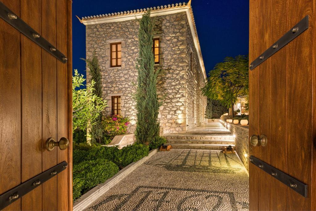 Mare Monte Luxury Suites في سبيتسيس: باب مفتوح يؤدي إلى منزل حجري مع درج