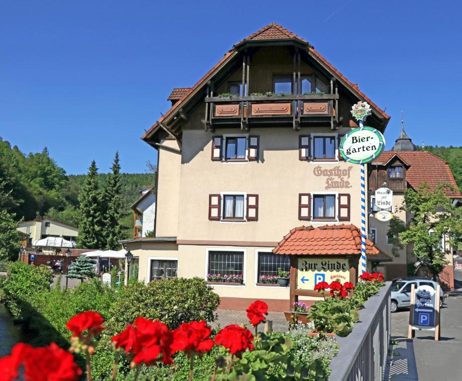 a large building with red flowers in front of it at Landgasthof zur Linde in Heimbuchenthal