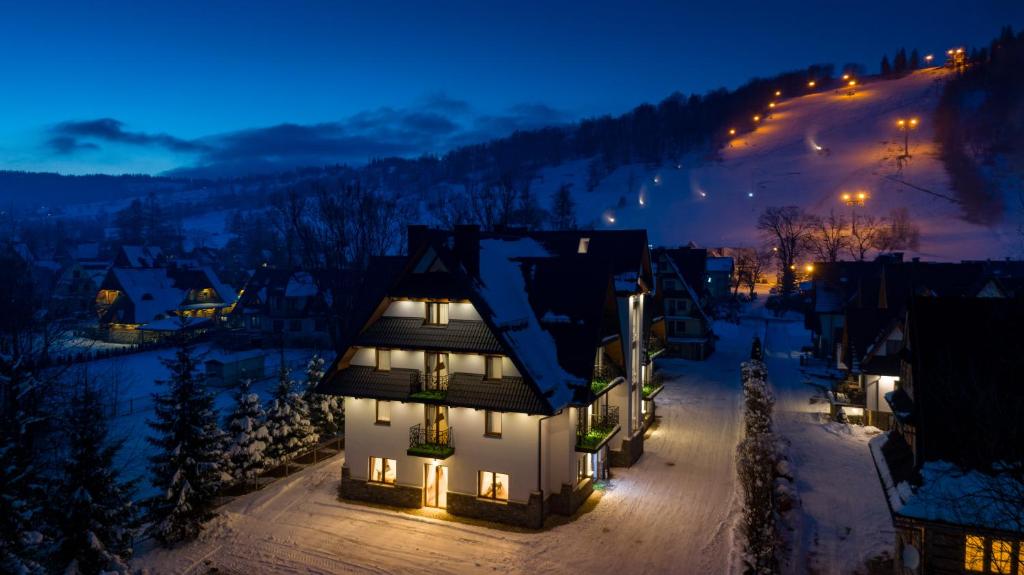 a house with lights on in the snow at night at Willa Stachoń in Zakopane