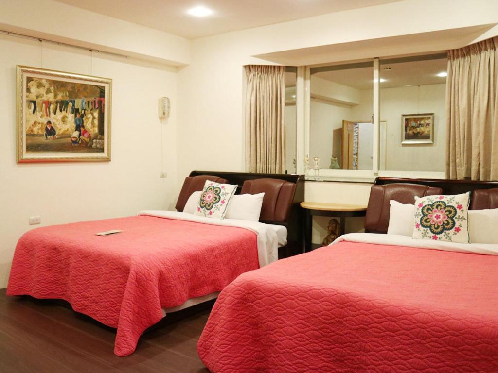 a hotel room with two beds with red sheets at Taichung Xinshe Garden Life Homestay B&amp;B in Xinshe