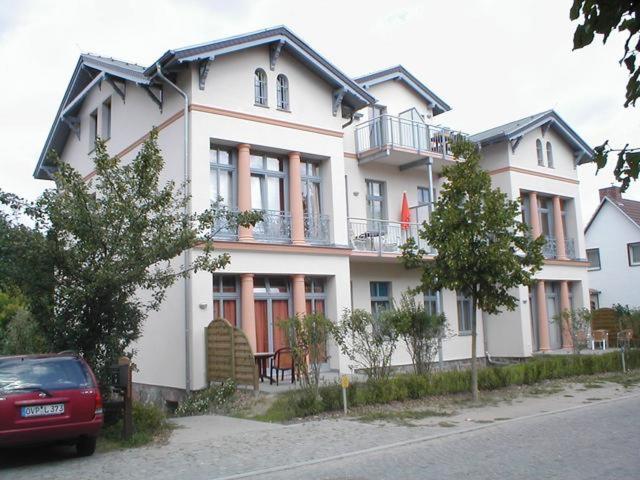 una grande casa bianca con una macchina rossa parcheggiata di fronte di Villa Inge Wohnung 6 a Heringsdorf