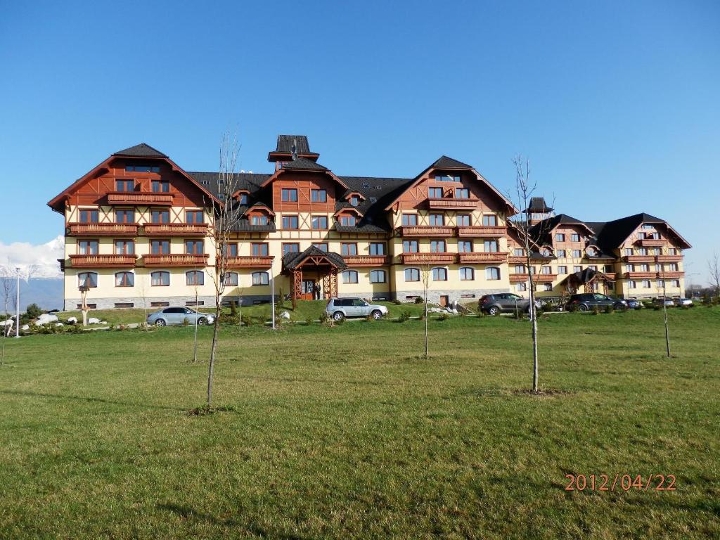 a large building with cars parked in front of it at APARTMÁN NELKA - VEĽKÁ LOMNICA in Veľká Lomnica