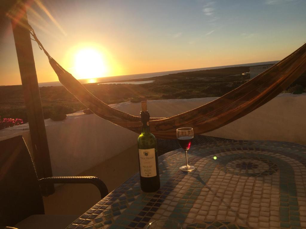 a bottle of wine and a glass on a table with the sunset at "Ziegenstall" mit Meerblick in Yaiza