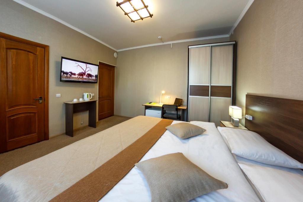 a bedroom with a large bed and a tv on the wall at Hotel Onega in Khabarovsk