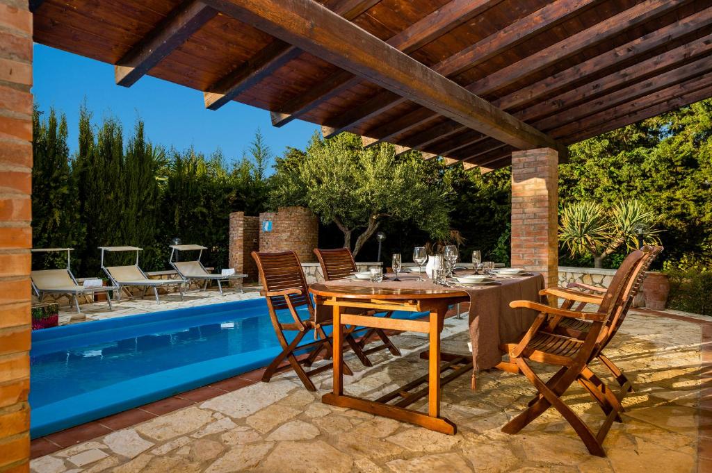 taras ze stołem i krzesłami obok basenu w obiekcie Villa Eden con piscina a Scopello w mieście Castellammare del Golfo