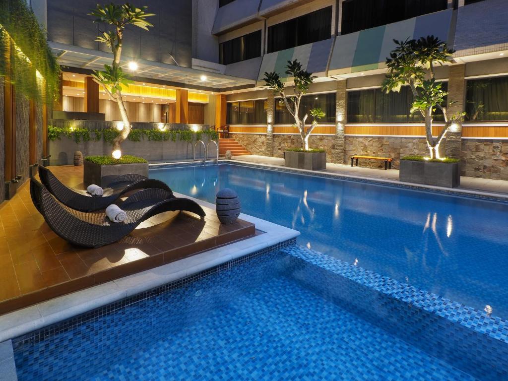 a hotel swimming pool with a hammock next to a building at Hotel Polonia Medan managed by Topotels in Medan