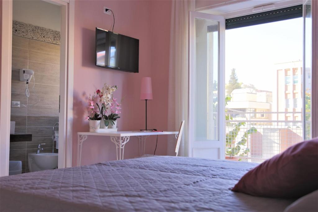 Un dormitorio con una cama y una mesa con flores. en B&B Rosa, en Cosenza