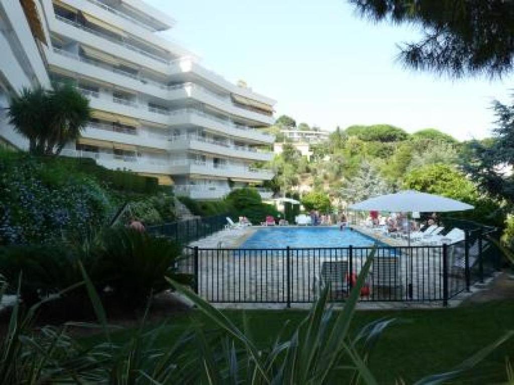 une piscine en face d'un grand bâtiment dans l'établissement Two Bed apartment in a gated residence with gardens in Cannes with sea views 865, à Cannes