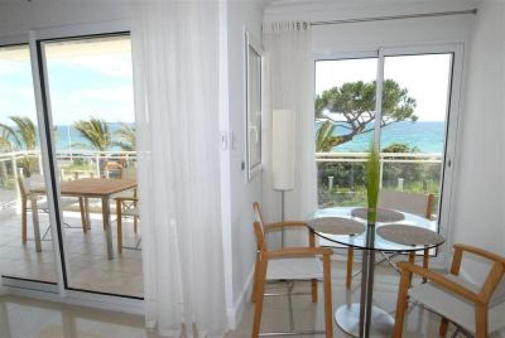 カンヌにあるStunning 2 Bed, 2 Bath Apt on the Cannes sea front has swimming pool and is a secure modern building 464のリビングルーム(テーブル、椅子付)、バルコニーが備わります。