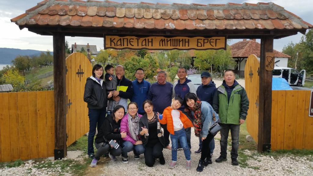 grupa ludzi stojących przed znakiem w obiekcie Etno Kompleks Kapetan Mišin breg w mieście Donji Milanovac