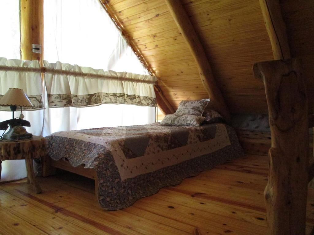 1 dormitorio con 1 cama en una cabaña de madera en Paraiso Bariloche en San Carlos de Bariloche