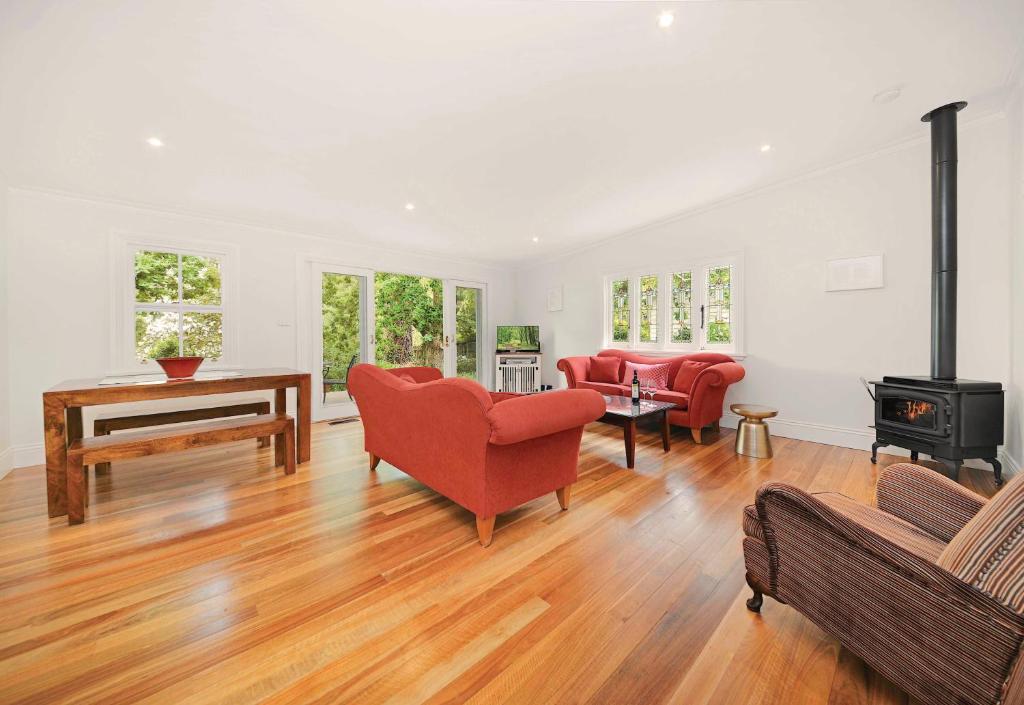 a living room with red chairs and a wood stove at Poet's Cottage - Fireplace, Close to Treks in Wentworth Falls