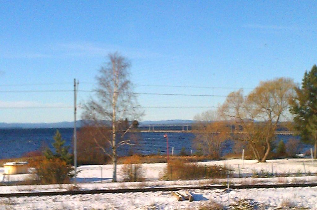 eine Zugstrecke mit Schnee auf dem Boden neben einem See in der Unterkunft Relax House Rättvik Spa Nordic in Rättvik