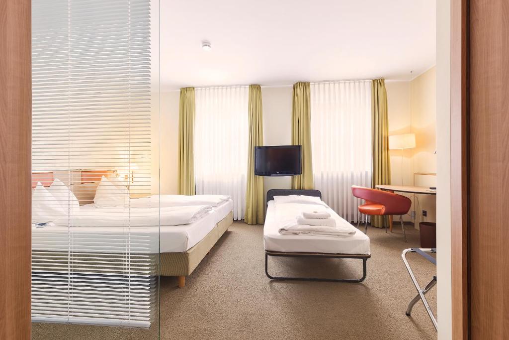 a hotel room with two beds and a desk at Hotel am Jakobsmarkt in Nuremberg