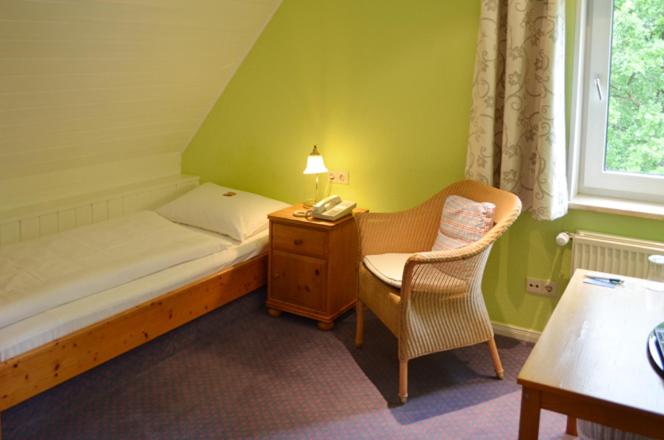 um quarto com uma cama, uma cadeira e um candeeiro em Finkenhof - Haus Meersmannufer em Hanôver