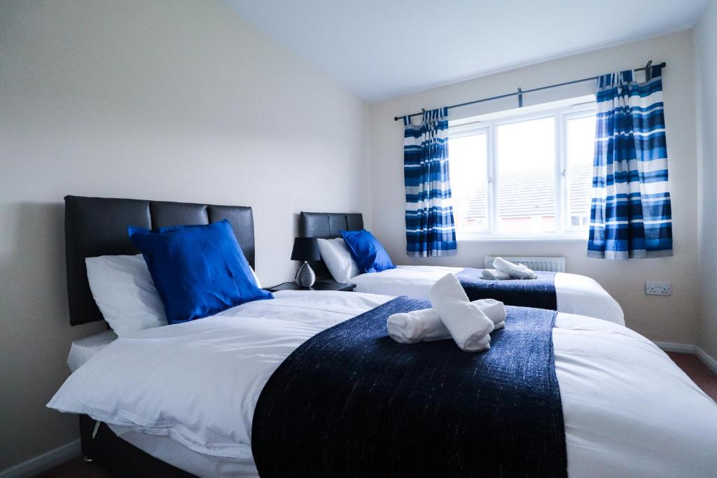 2 łóżka w sypialni w kolorze niebieskim i białym w obiekcie Royal Oak Home w mieście Wythenshawe