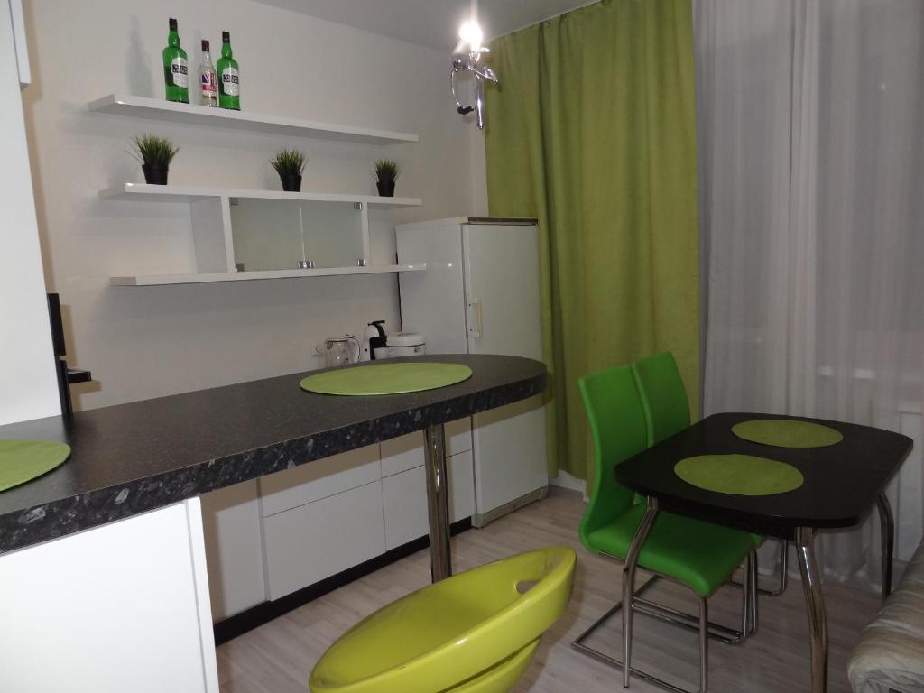 a kitchen with green chairs and a counter with a table at Apartment on Aviatorov 23 in Krasnoyarsk