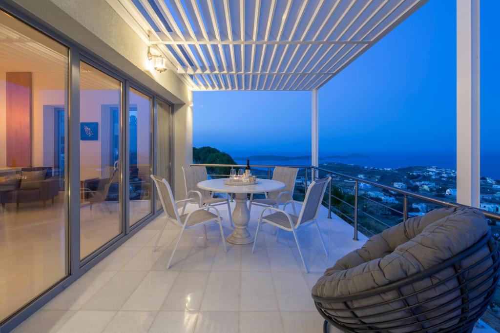 a dining room with a table and chairs on a balcony at Syros Luxury Living in Rózia