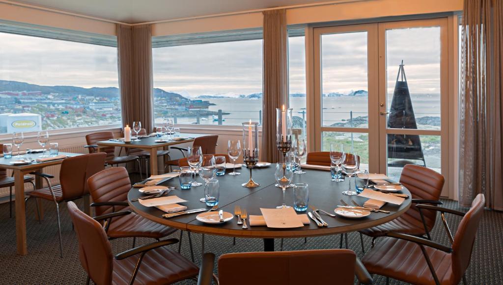 a restaurant with tables and chairs and a large window at Hotel Arctic in Ilulissat