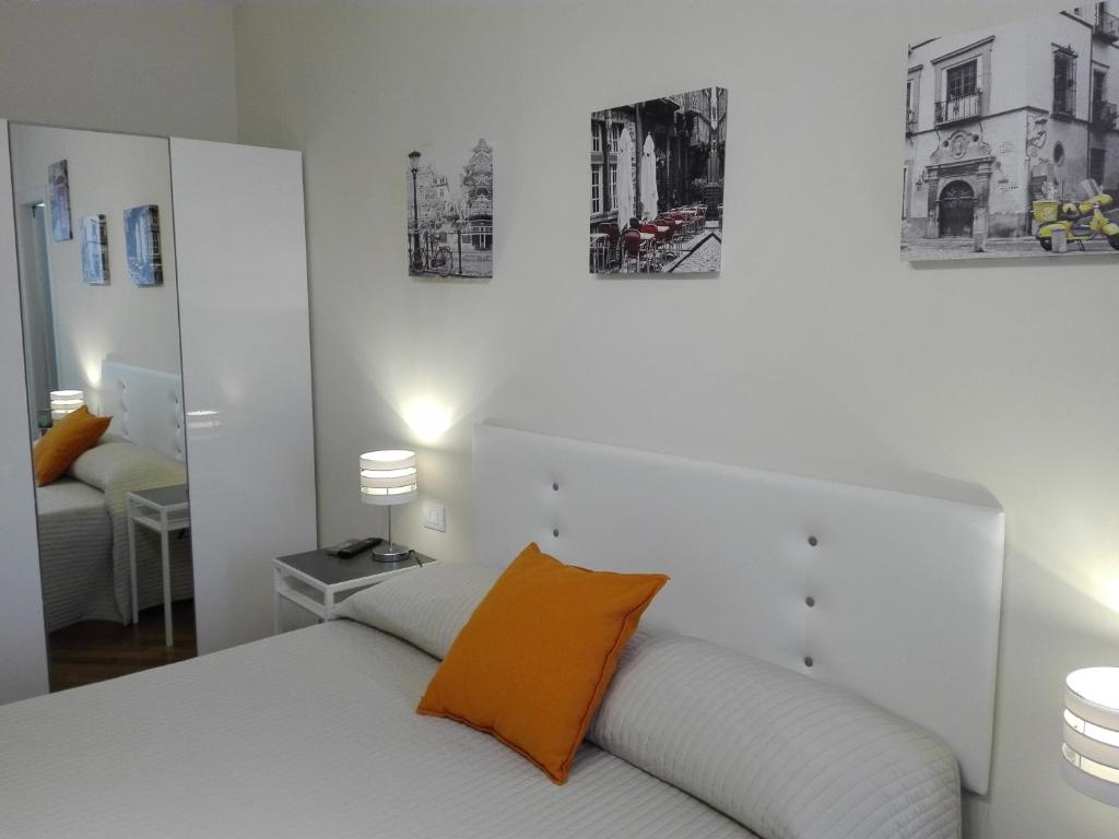 1 dormitorio con cama blanca y almohada naranja en Residenza Piazza Moro, en Bari