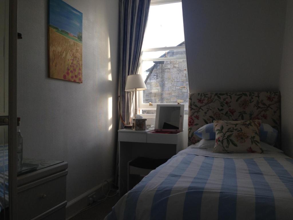 a small bedroom with a bed and a window at Doune Guest House in St Andrews