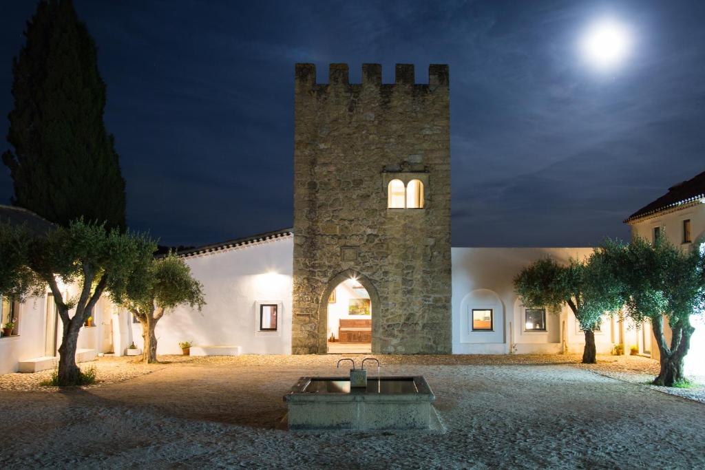 un bâtiment avec une tour d'horloge la nuit dans l'établissement Herdade da Maxuqueira, à Gavião