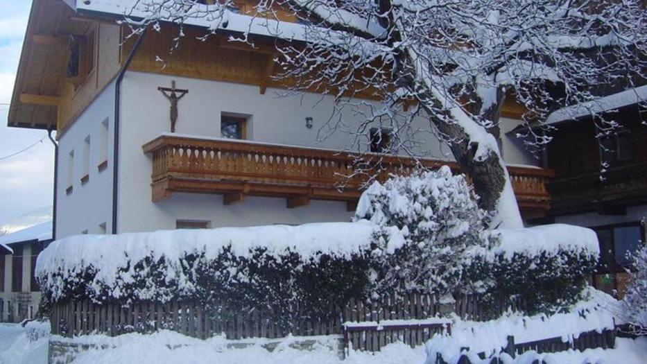 uma casa com uma varanda de madeira na neve em Kundlerhof em Stilves