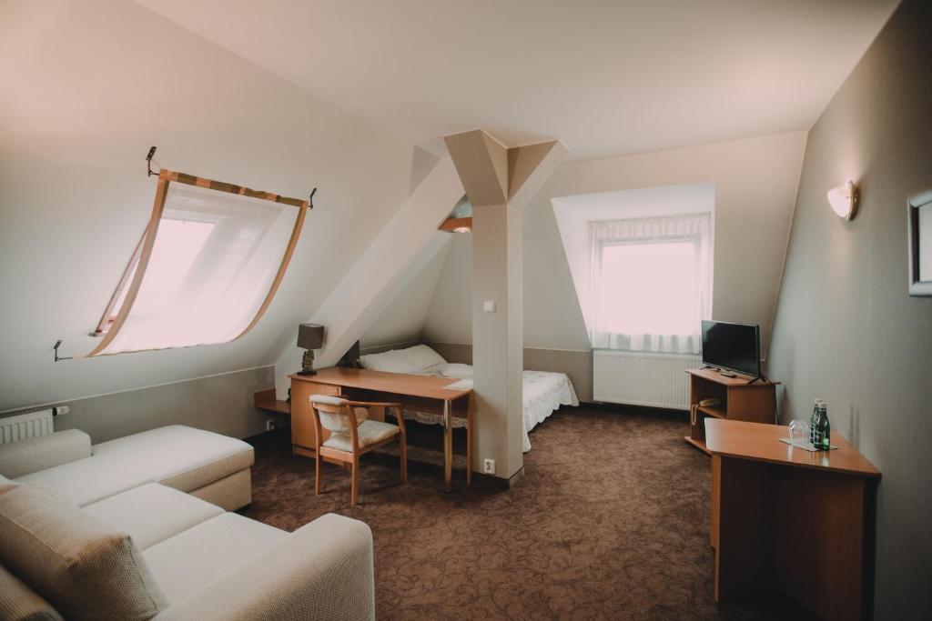 una sala de estar con cama y escritorio y una habitación en Hotel Restaurant Boss, en Miłosław