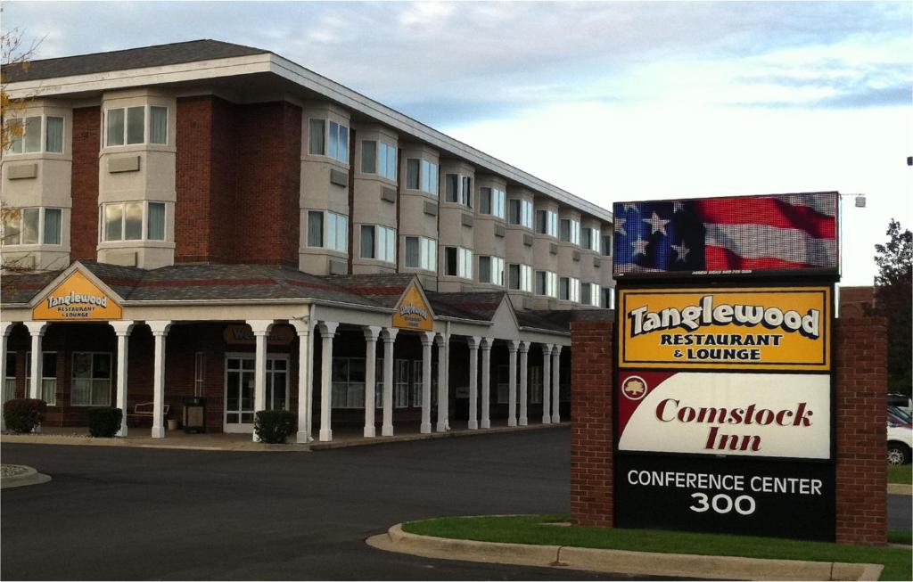 un hotel con un cartello di fronte a un edificio di Comstock Inn & Conference Center a Owosso