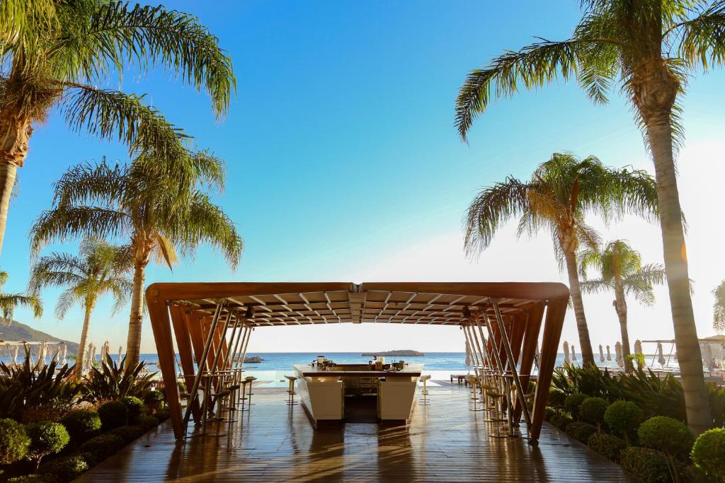 a table and chairs under a pavilion on the beach at Alimounda Mare Hotel in Karpathos