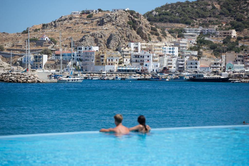 a woman laying on a beach next to a body of water at Alimounda Mare Hotel in Karpathos Town