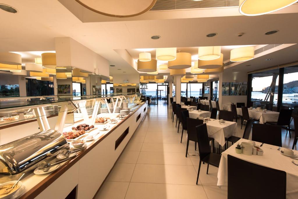 a restaurant with white tables and black chairs at Alimounda Mare Hotel in Karpathos