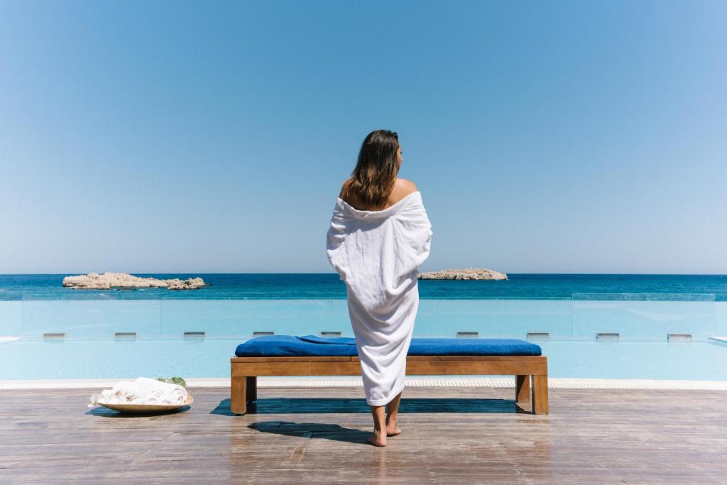 a woman in a towel standing on a bed at the beach at Alimounda Mare Hotel in Karpathos