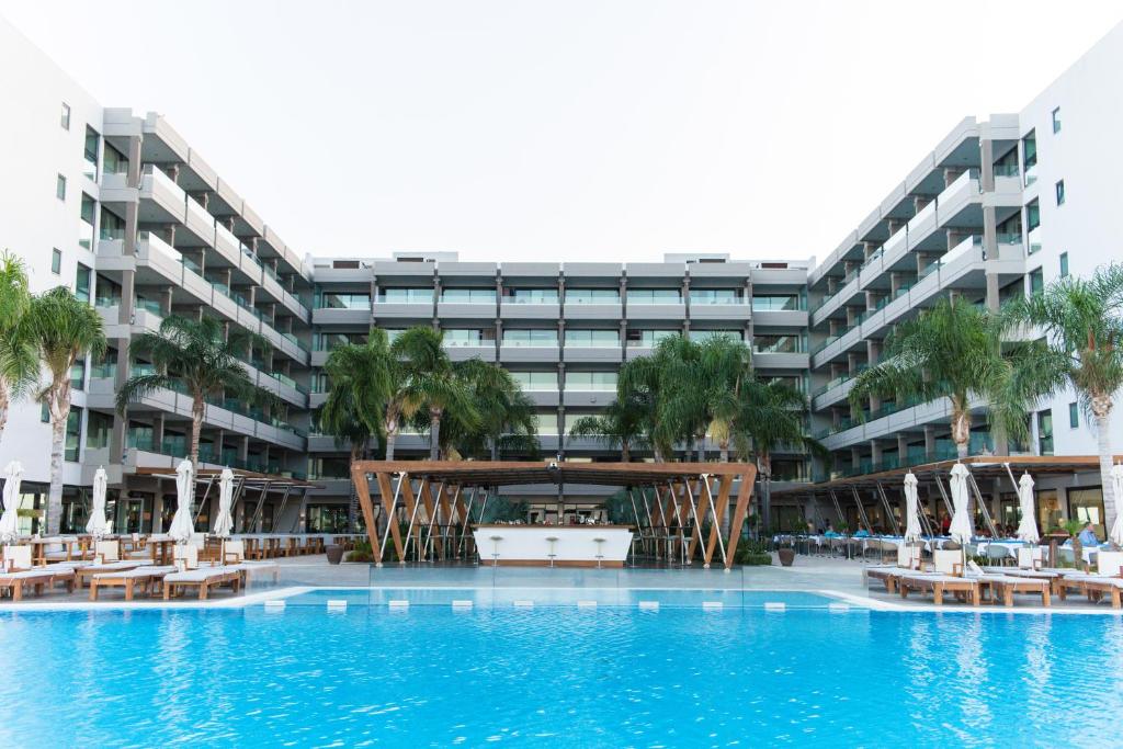 an exterior view of a large apartment building with a swimming pool at Alimounda Mare Hotel in Karpathos