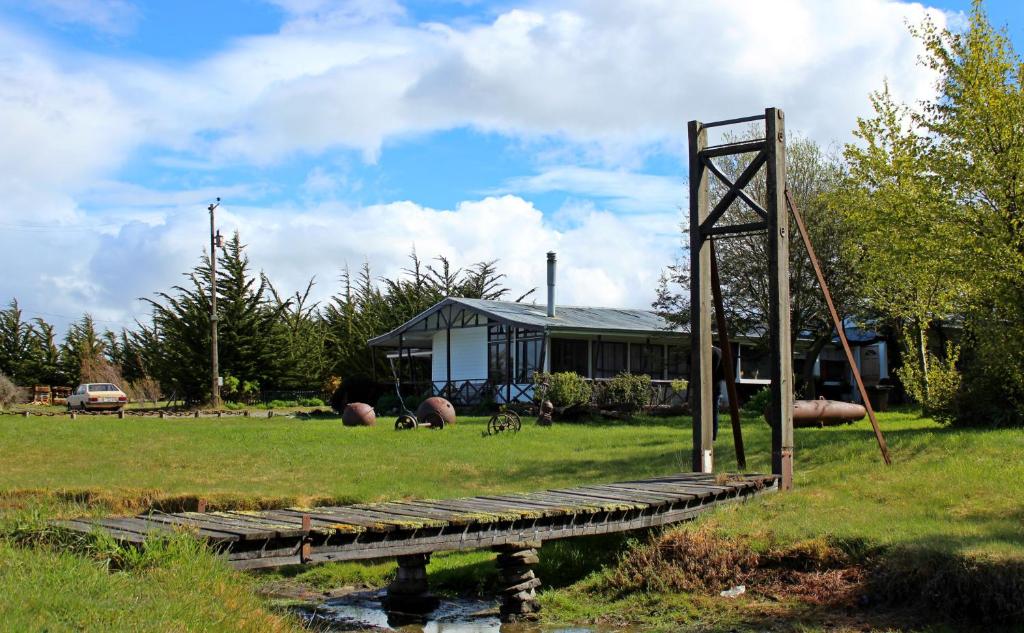 un ponte sopra un laghetto di fronte a una casa di Hospedaje Isla Magdalena a Punta Arenas