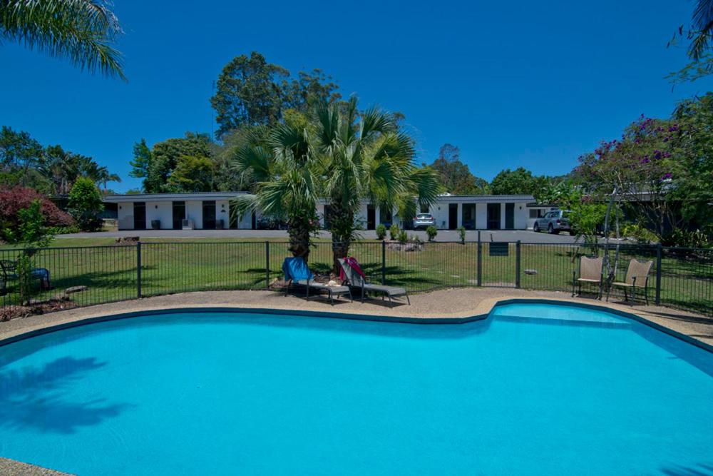 a person sitting in a chair next to a swimming pool at Buderim Fiesta Motel in Tanawha