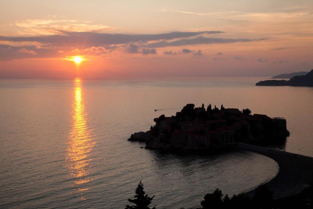 a sunset over a small island in the water at Villa Edelweiss in Sveti Stefan