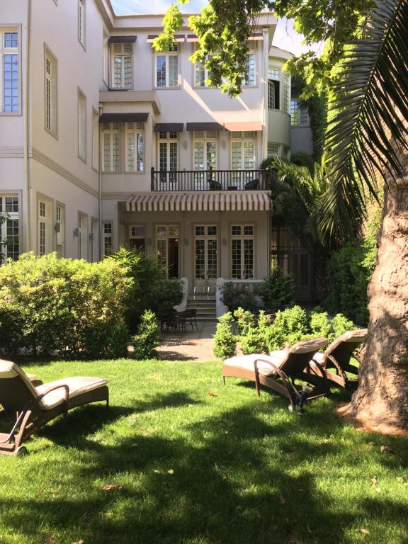 eine Gruppe von Stühlen, die im Gras vor einem Gebäude sitzen in der Unterkunft Matildas Hotel Boutique in Santiago