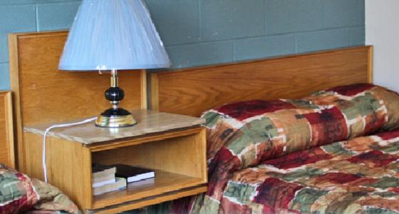 a lamp on a night stand next to a bed at Cedar Inn in Lloydminster