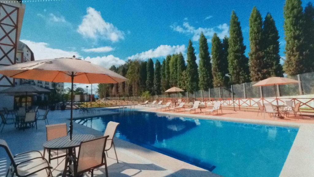 uma piscina com cadeiras, mesas e guarda-sóis em Condomínio Vista azul em Domingos Martins
