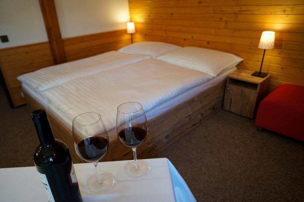 2 Gläser Wein auf einem Tisch mit einem Bett in der Unterkunft Penzion Čistá in Černý Důl