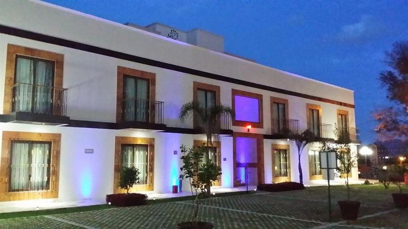 阿特利斯科的住宿－Soleil Inn Atlixco，一座白色的大建筑,上面有紫色的灯