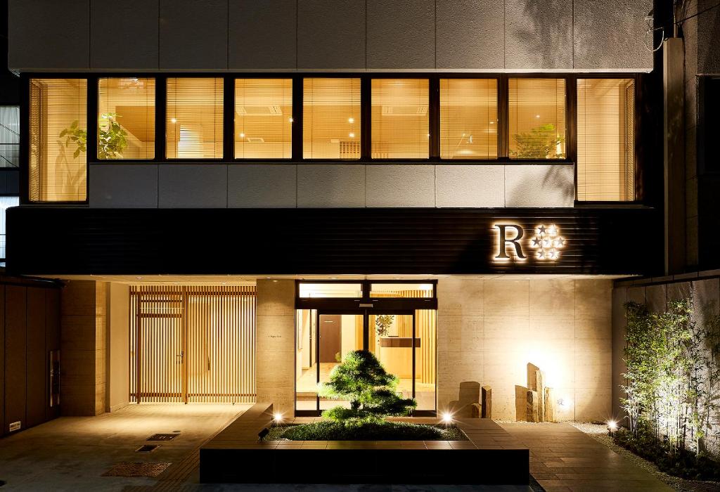 un edificio con un árbol delante de él en R Star Hostel Kyoto en Kioto