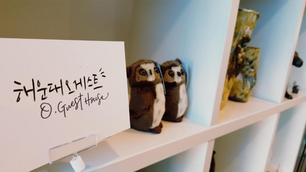 dos pingüinos de peluche sentados en un estante junto a una señal en O'guest in Haeundae, en Busan