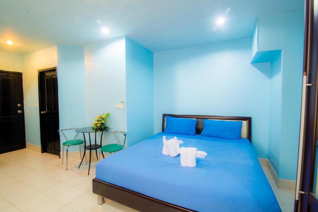a blue bedroom with a bed and a table at DE Apartment in Pattaya South