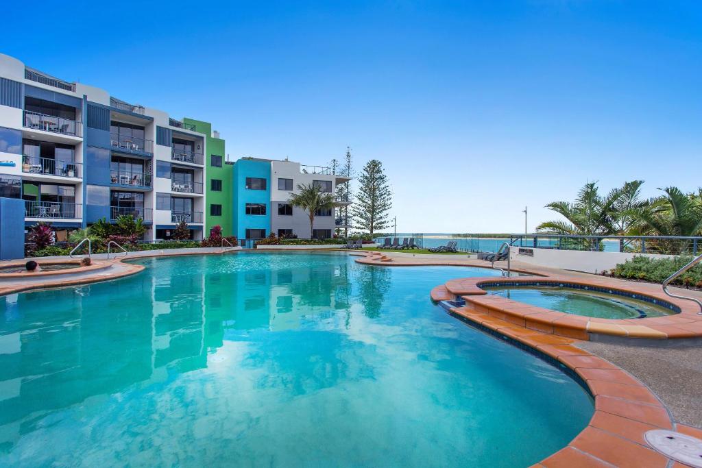 a large swimming pool with blue water in front of apartment buildings at BreakFree Grand Pacific in Caloundra