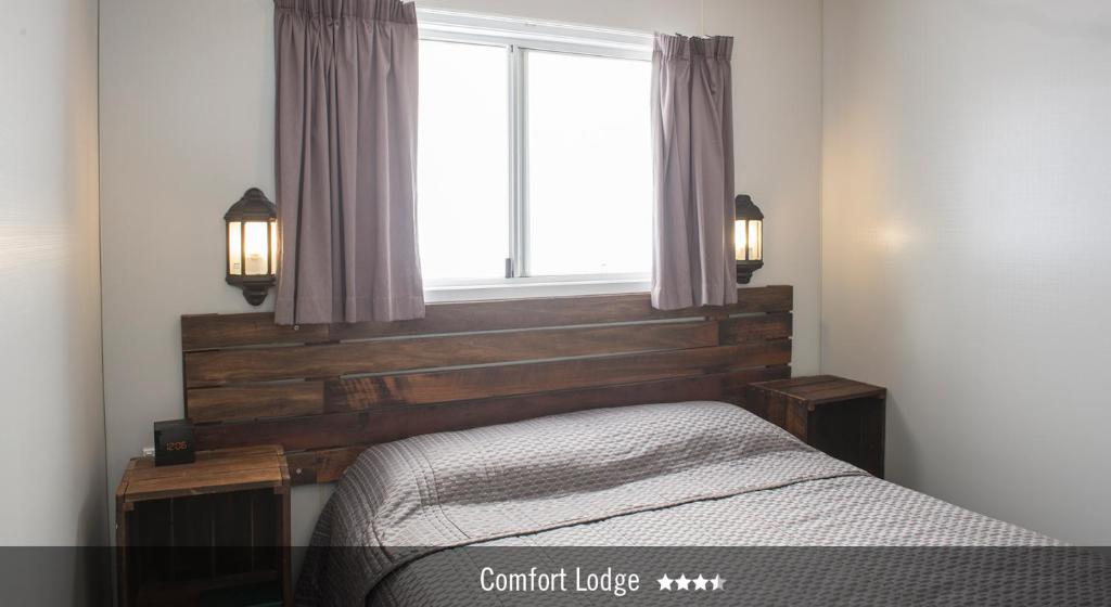 a bedroom with a wooden headboard and a window at Saltbush Retreat in Longreach